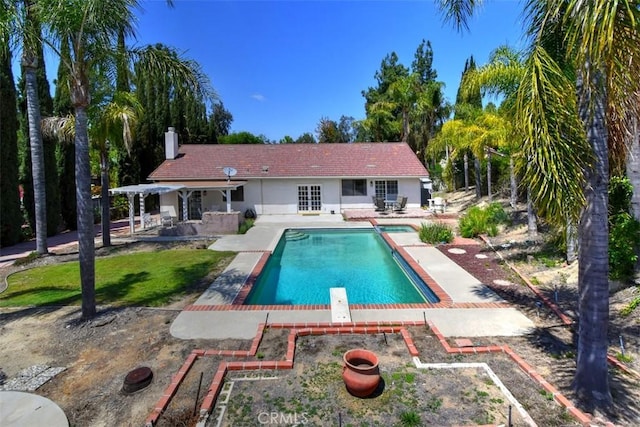 rear view of house featuring a patio, an outdoor pool, stucco siding, and a garden