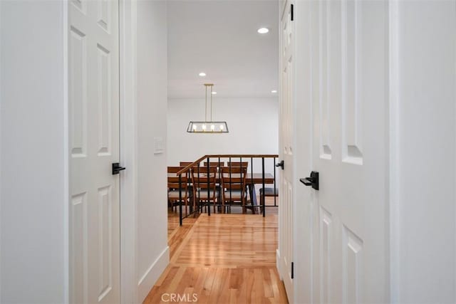 hall featuring recessed lighting, baseboards, a notable chandelier, and light wood-style floors