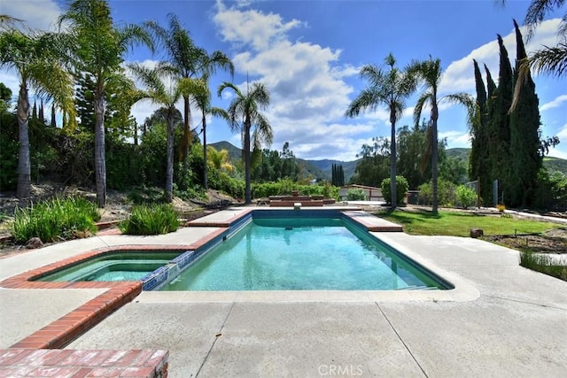 view of pool featuring a mountain view, a pool with connected hot tub, and a patio