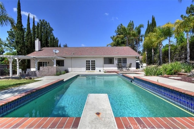 outdoor pool with a diving board and a patio area