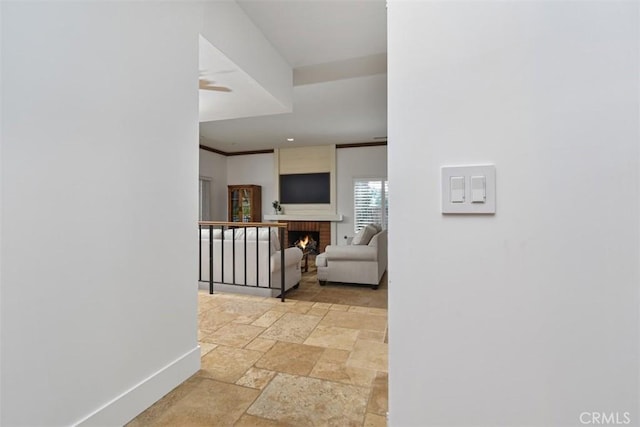 hall featuring baseboards and stone tile flooring