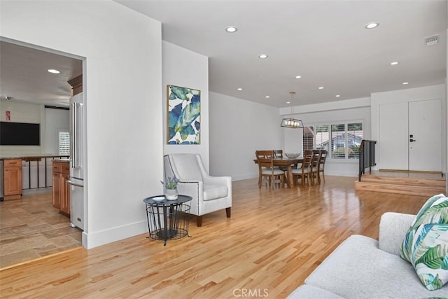 living area featuring light wood-style floors, baseboards, recessed lighting, and visible vents