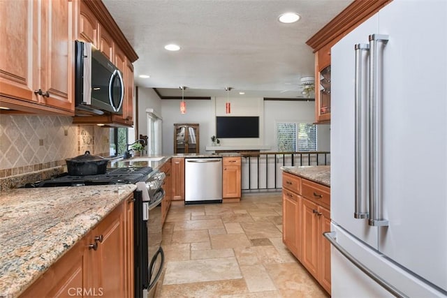 kitchen with appliances with stainless steel finishes, light stone counters, stone tile floors, recessed lighting, and tasteful backsplash