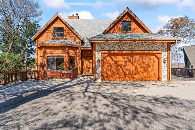1305 Montreal Dr, Lake Arrowhead, CA 92352 - view of front of house with a garage, stone siding, roof with shingles, a chimney, and driveway
