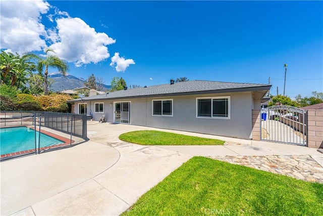back of property with fence, stucco siding, a fenced in pool, a gate, and a patio area