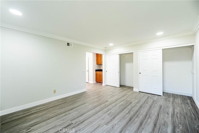 unfurnished bedroom with visible vents, crown molding, multiple closets, baseboards, and light wood-style floors