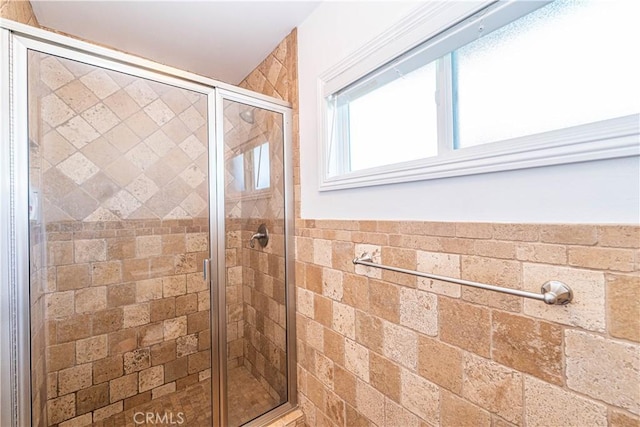 bathroom with a stall shower and tile walls