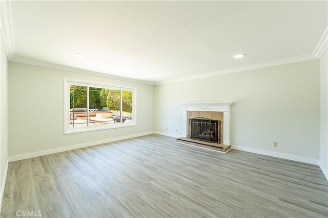 unfurnished living room featuring baseboards, ornamental molding, light wood-style flooring, and a fireplace