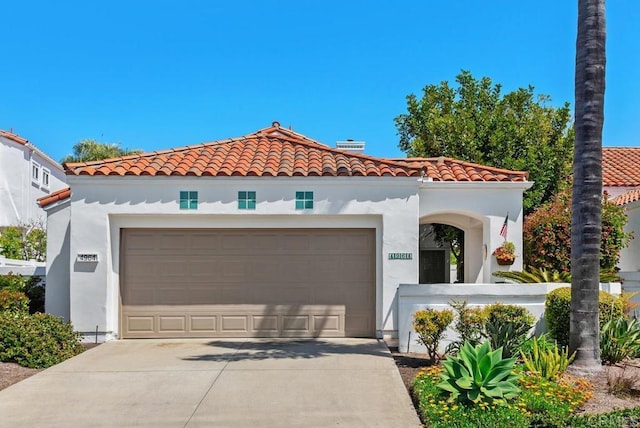 mediterranean / spanish-style house featuring an attached garage, stucco siding, a tile roof, and concrete driveway