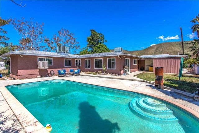 back of property with a mountain view, an outdoor pool, a patio area, and stucco siding