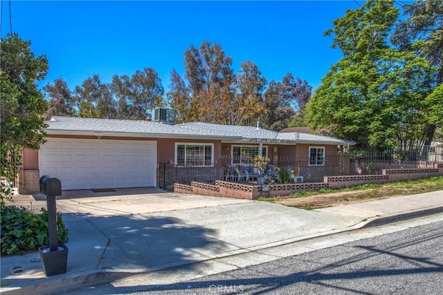single story home with an attached garage, driveway, a fenced front yard, and stucco siding