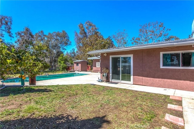 outdoor pool with a storage unit, an outdoor structure, a yard, and a patio area