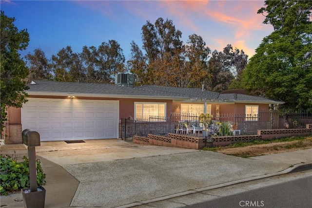 ranch-style house featuring a garage, cooling unit, stucco siding, concrete driveway, and a fenced front yard