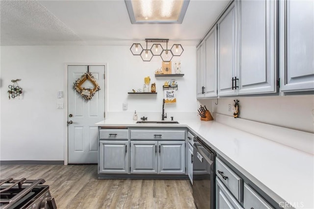 kitchen featuring a sink, light wood-style floors, light countertops, stainless steel appliances, and gray cabinetry