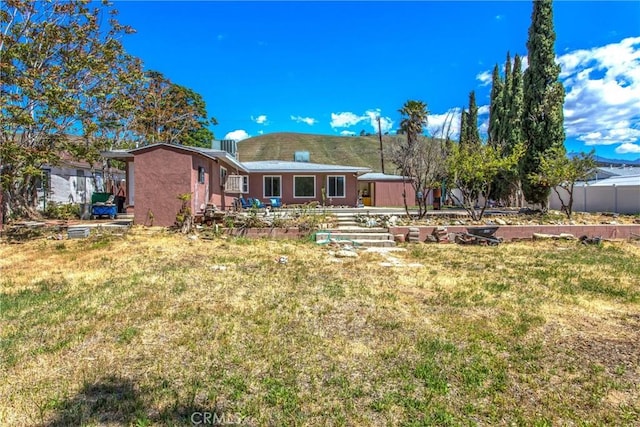 back of property featuring a lawn and fence