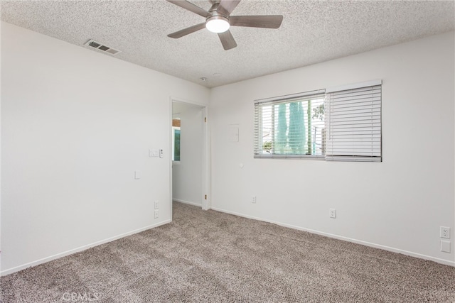 carpeted spare room featuring visible vents, a textured ceiling, ceiling fan, and baseboards