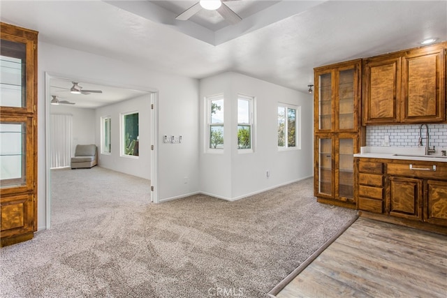 kitchen with ceiling fan, tasteful backsplash, brown cabinets, a sink, and open floor plan