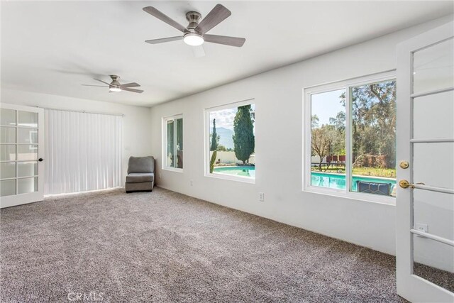 unfurnished room with a ceiling fan and carpet