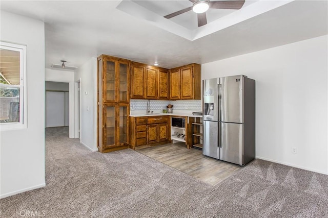 kitchen with light carpet, ceiling fan, built in microwave, brown cabinets, and stainless steel fridge with ice dispenser