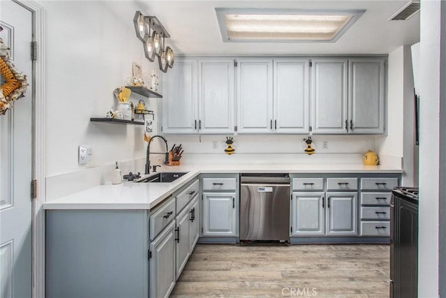kitchen featuring stainless steel dishwasher, a sink, gray cabinets, and light wood-style floors