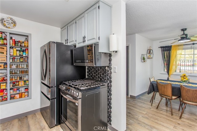 kitchen with a ceiling fan, tasteful backsplash, light wood-type flooring, baseboards, and stainless steel appliances