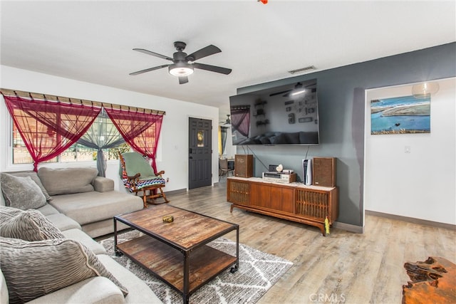 living area with visible vents, a ceiling fan, baseboards, and light wood-style floors