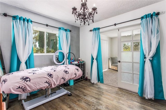 bedroom featuring an inviting chandelier, a textured ceiling, and wood finished floors