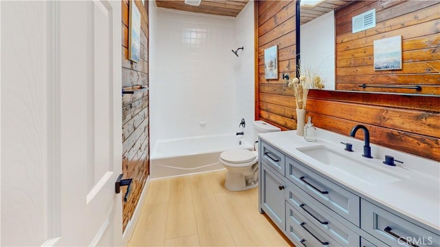 bathroom with wood walls, toilet, wood finished floors, vanity, and washtub / shower combination