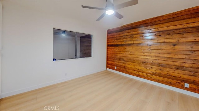 spare room featuring light wood-style flooring, baseboards, and a ceiling fan