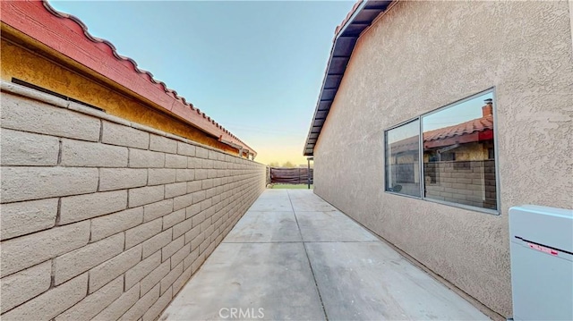 property exterior at dusk with stucco siding, fence, and a patio