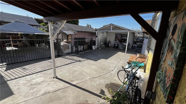 view of patio / terrace featuring an outdoor structure, fence, and a storage shed