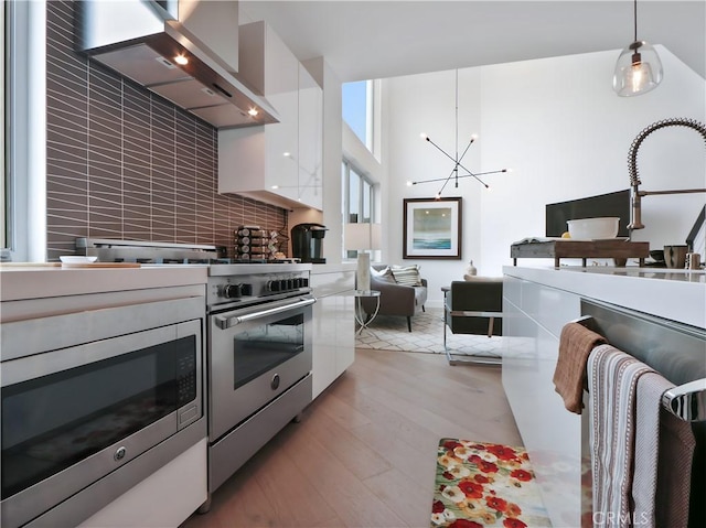 kitchen featuring wall chimney exhaust hood, appliances with stainless steel finishes, modern cabinets, and white cabinets