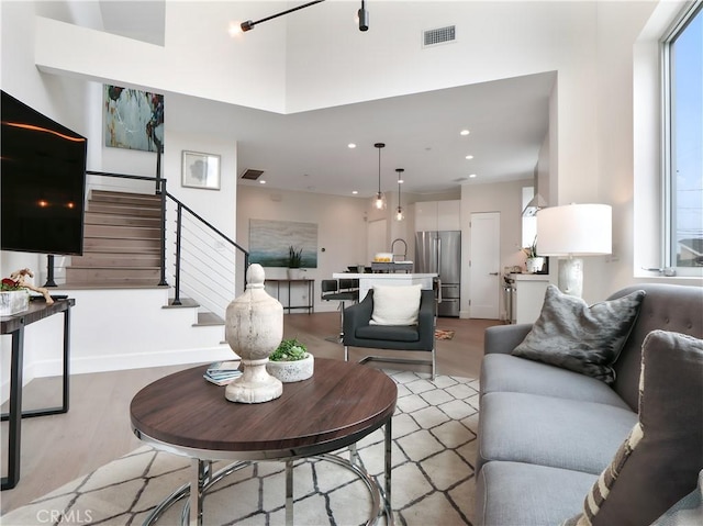 living room with light wood-style floors, recessed lighting, stairs, and visible vents