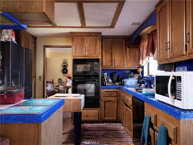 kitchen featuring backsplash, brown cabinets, visible vents, and black appliances