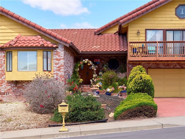 view of front of home featuring a garage, a tiled roof, and brick siding