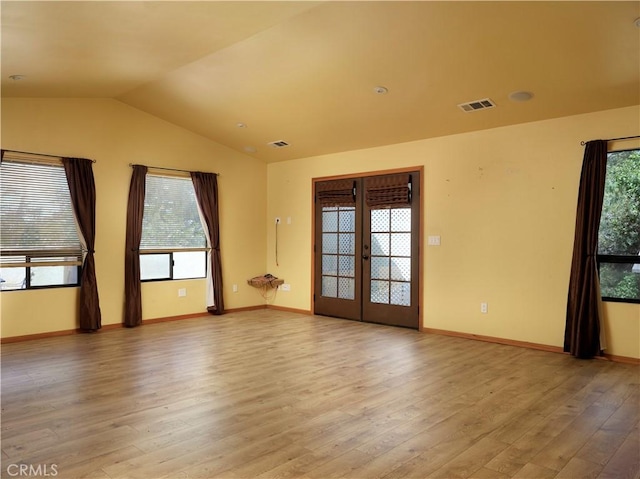 empty room featuring visible vents, light wood-style flooring, a healthy amount of sunlight, and french doors