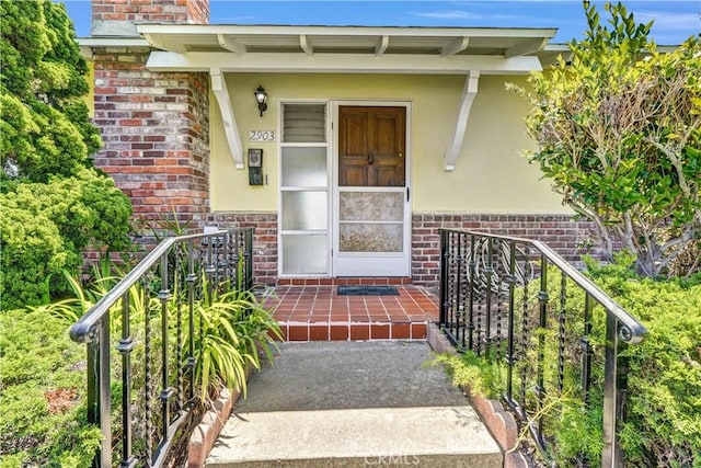 property entrance featuring brick siding, stucco siding, and a chimney
