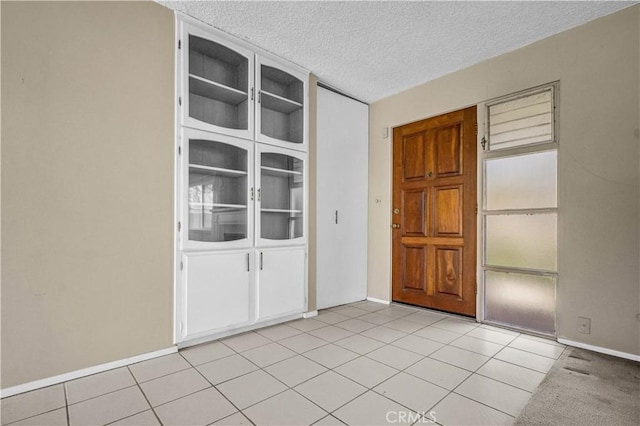 spare room with light tile patterned floors, baseboards, and a textured ceiling