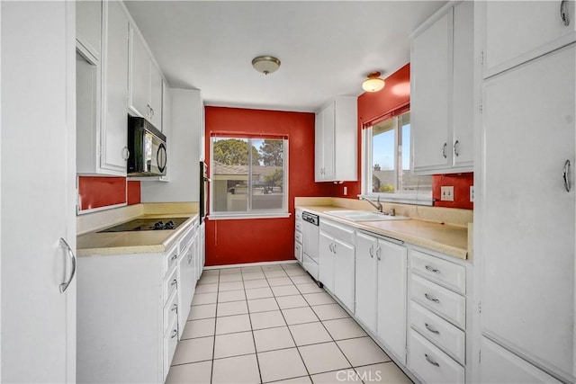 kitchen with a sink, white cabinets, black appliances, and light countertops