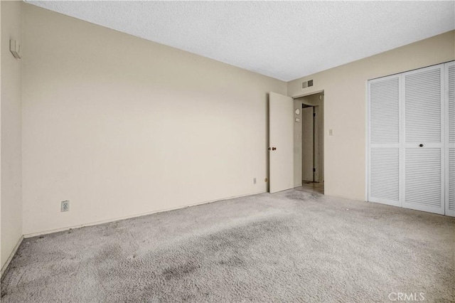 unfurnished bedroom featuring carpet floors, a closet, a textured ceiling, and visible vents