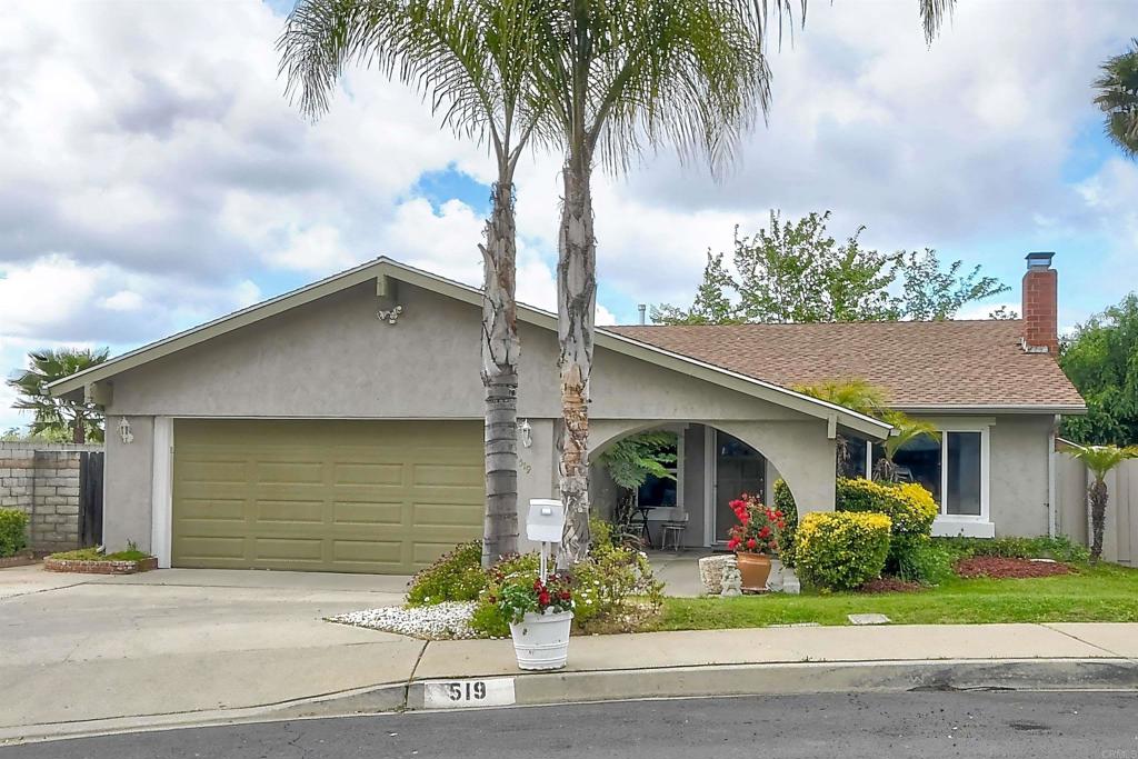 ranch-style house featuring driveway, a chimney, fence, an attached garage, and stucco siding