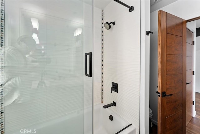 bathroom featuring combined bath / shower with glass door and toilet