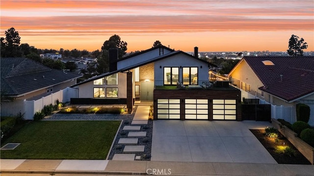 contemporary house with fence, an attached garage, a yard, and driveway