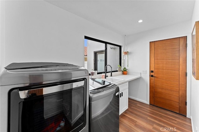 kitchen featuring white cabinets, a sink, light countertops, recessed lighting, and wood finished floors