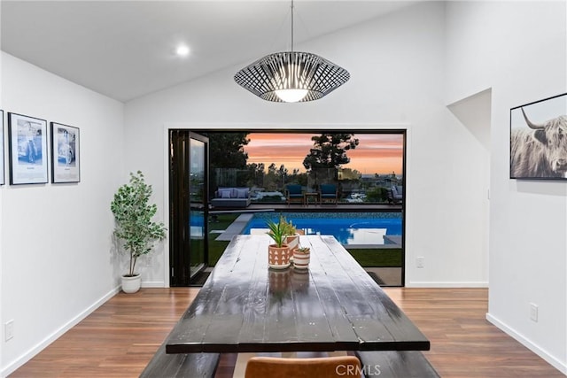 dining room featuring baseboards, wood finished floors, and vaulted ceiling