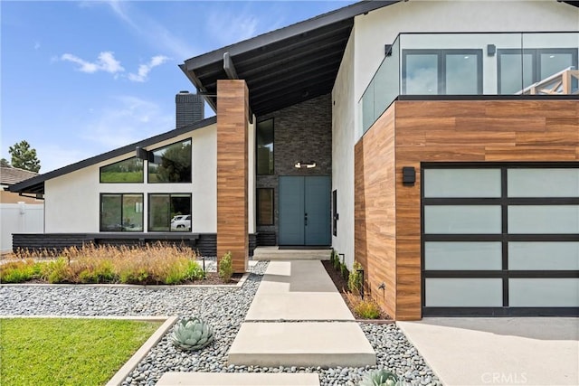 view of front facade featuring stucco siding, an attached garage, and a chimney