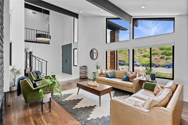 living room with stairs, baseboards, wood finished floors, and a towering ceiling