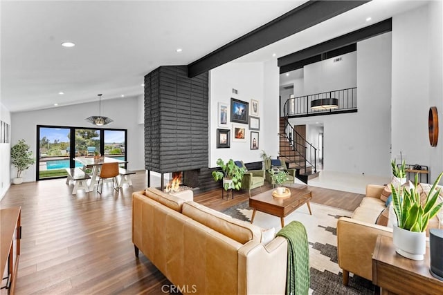living area featuring recessed lighting, high vaulted ceiling, wood finished floors, and stairway