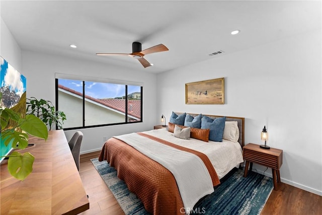 bedroom featuring baseboards, a ceiling fan, wood finished floors, and visible vents