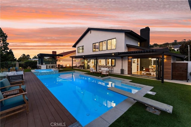 back of house at dusk with fence, an outdoor bar, a chimney, a patio area, and a yard